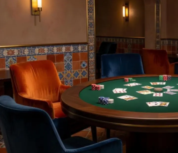 Card lounge íntimo con mesa de póker, cartas y fichas en un entorno mediterráneo sofisticado.